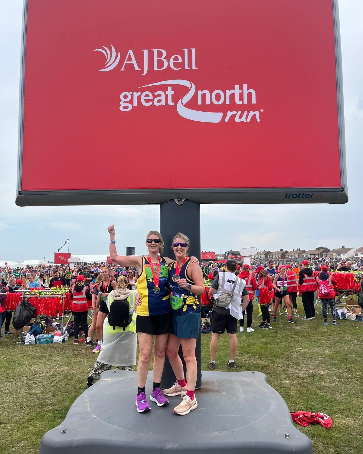 Two female runners stood with their medals underneath the Great North Run sign