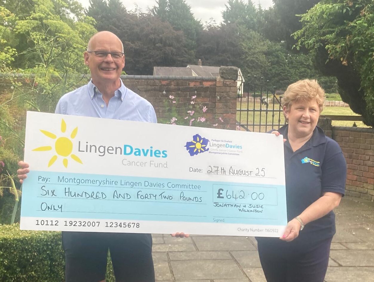 Two people stand outdoors smiling while holding an oversized cheque for £642 made out to the Lingen Davies Cancer Support, dated 27th August 2025.